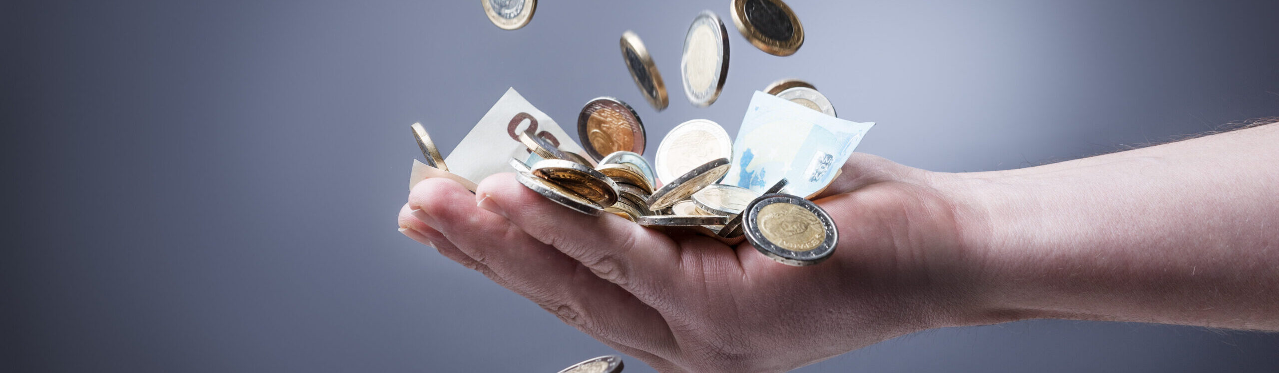 Geld rieselt in eine offene Hand