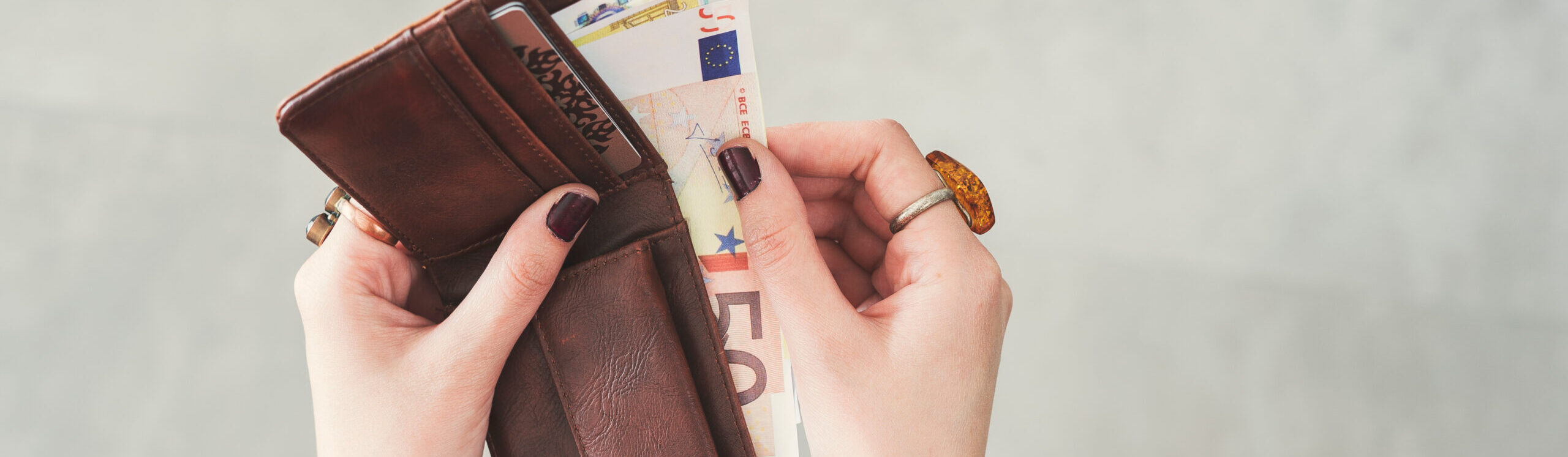 Zwei Hände umfassen eine Geldbörse mit einem Geldschein