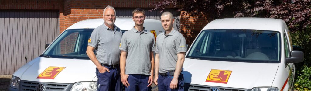Der Auszubildende mit seinen Chefs vor den Firmenwagen
