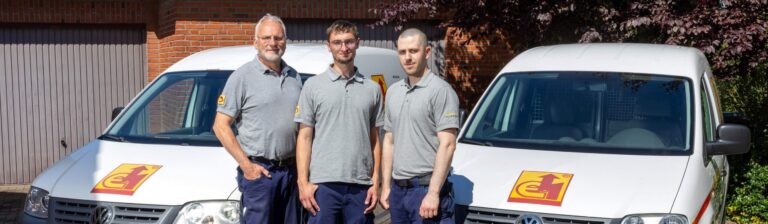 Der Auszubildende mit seinen Chefs vor den Firmenwagen