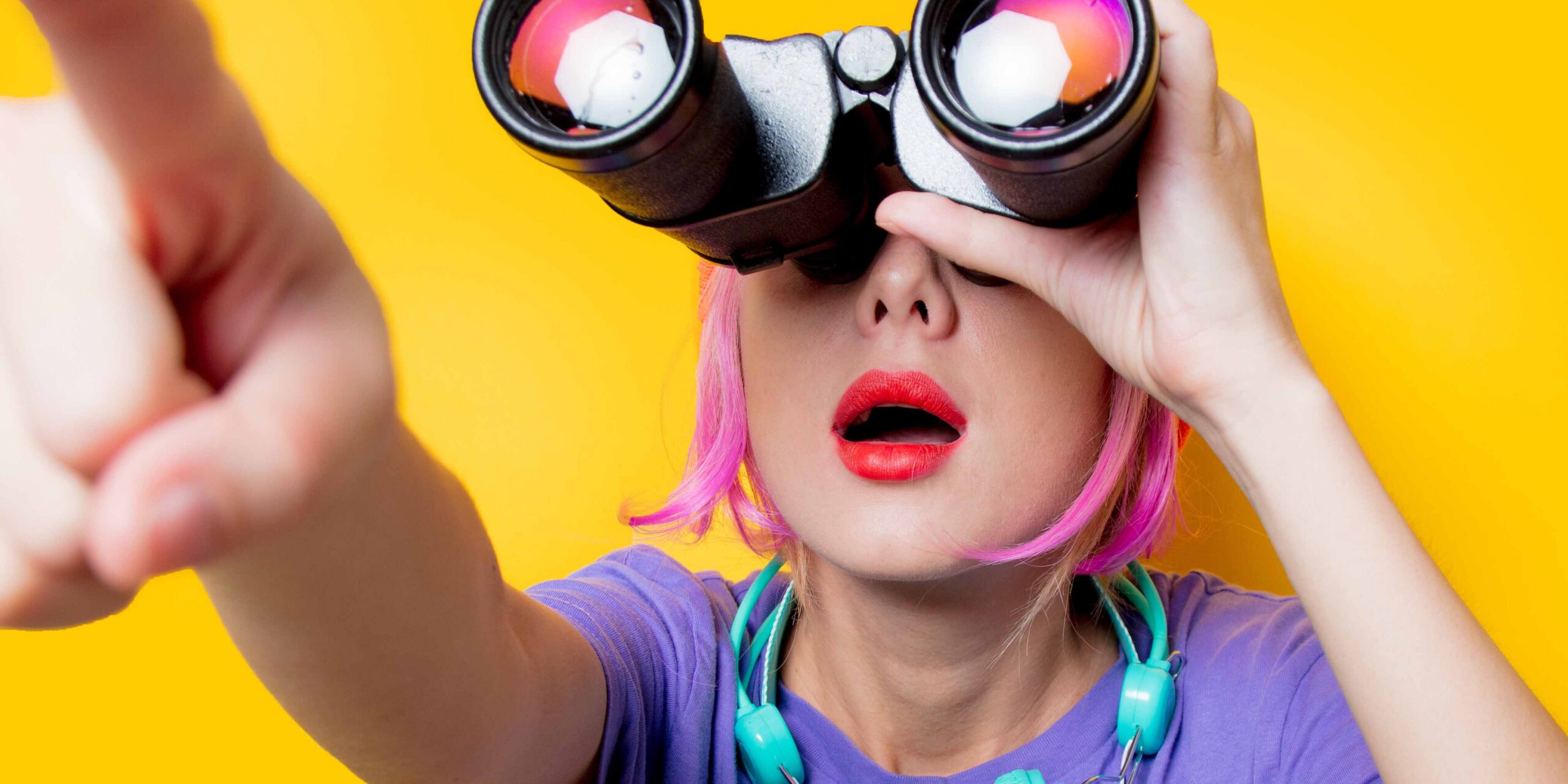 Frau mit Fernglas zeigt in die Ferne