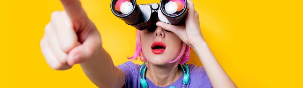 Frau mit Fernglas zeigt in die Ferne
